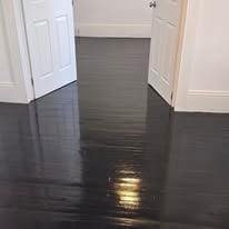 Dark stained wood floor in hallway with white baseboards and gray panel accent wall
