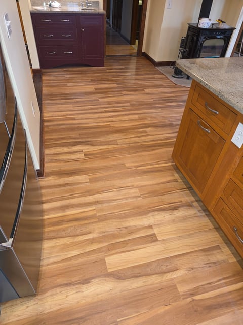 Modern kitchen with hardwood flooring, wooden cabinets, stainless steel appliances, and granite countertops