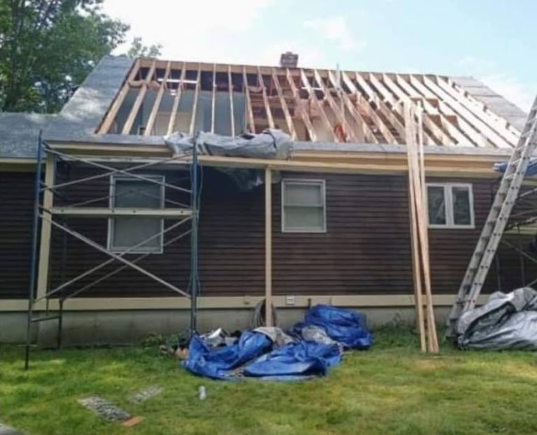 House undergoing roof replacement with exposed wooden beams, metal scaffolding, and blue tarps on the ground