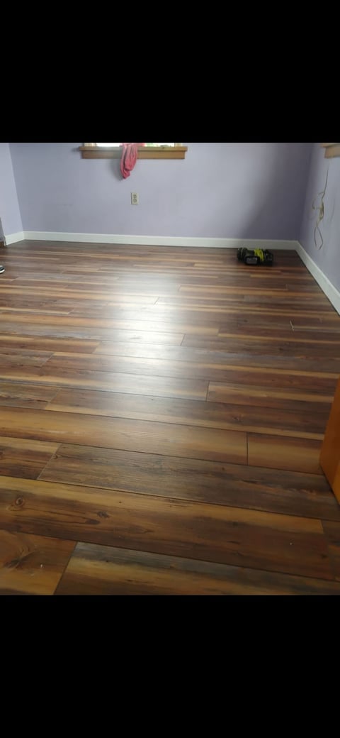 Empty room with laminate wood flooring, white walls, and a wooden wall-mounted pull-up bar with pink towel